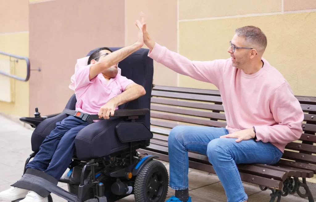 Disabled man high fiving support worker