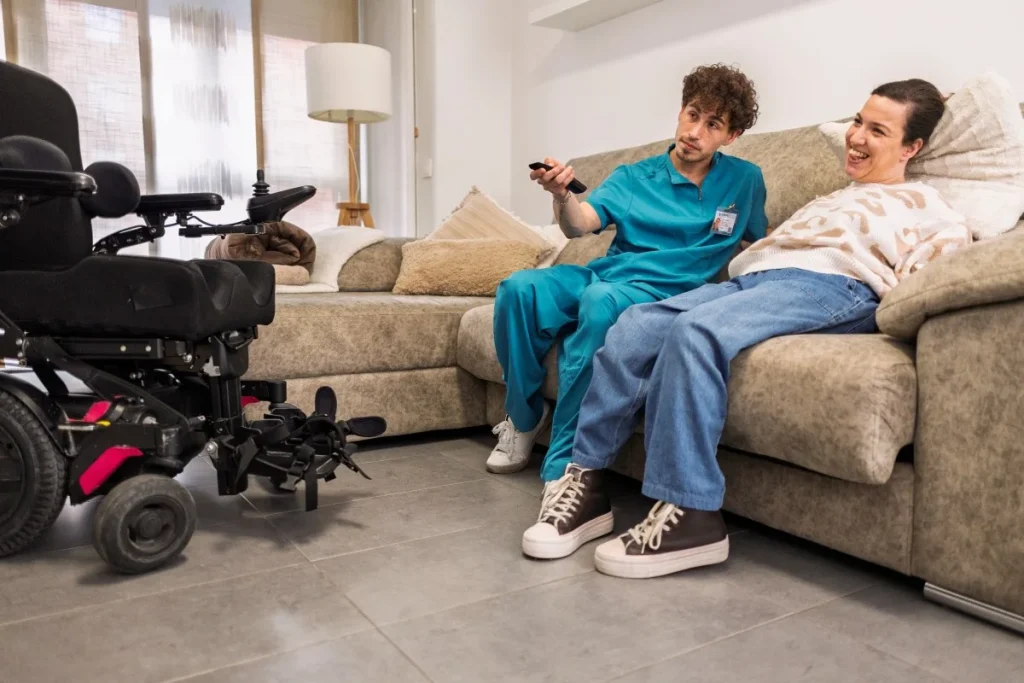 Nurse with disabled woman watching TV on couch