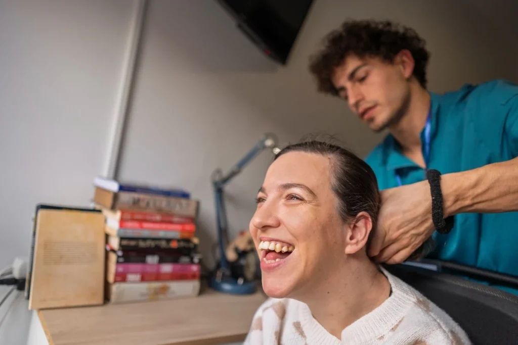 Disabled woman smiling as nurse does hair